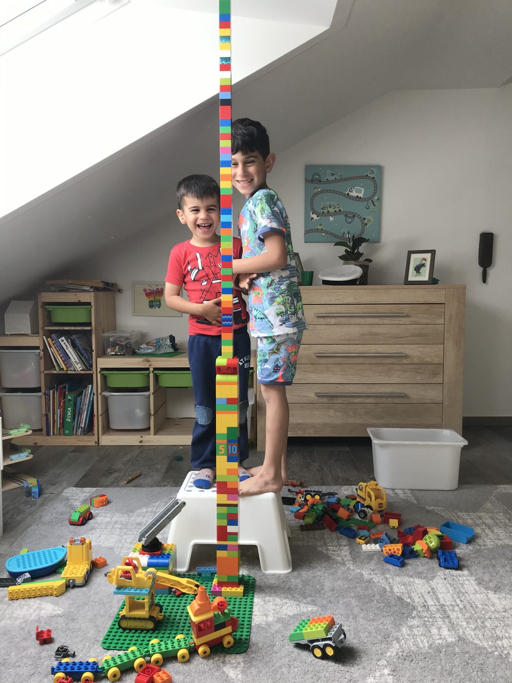 Zwei Brüder bauen gemeinsam einen Turm aus Bausteinen bis zur Decke